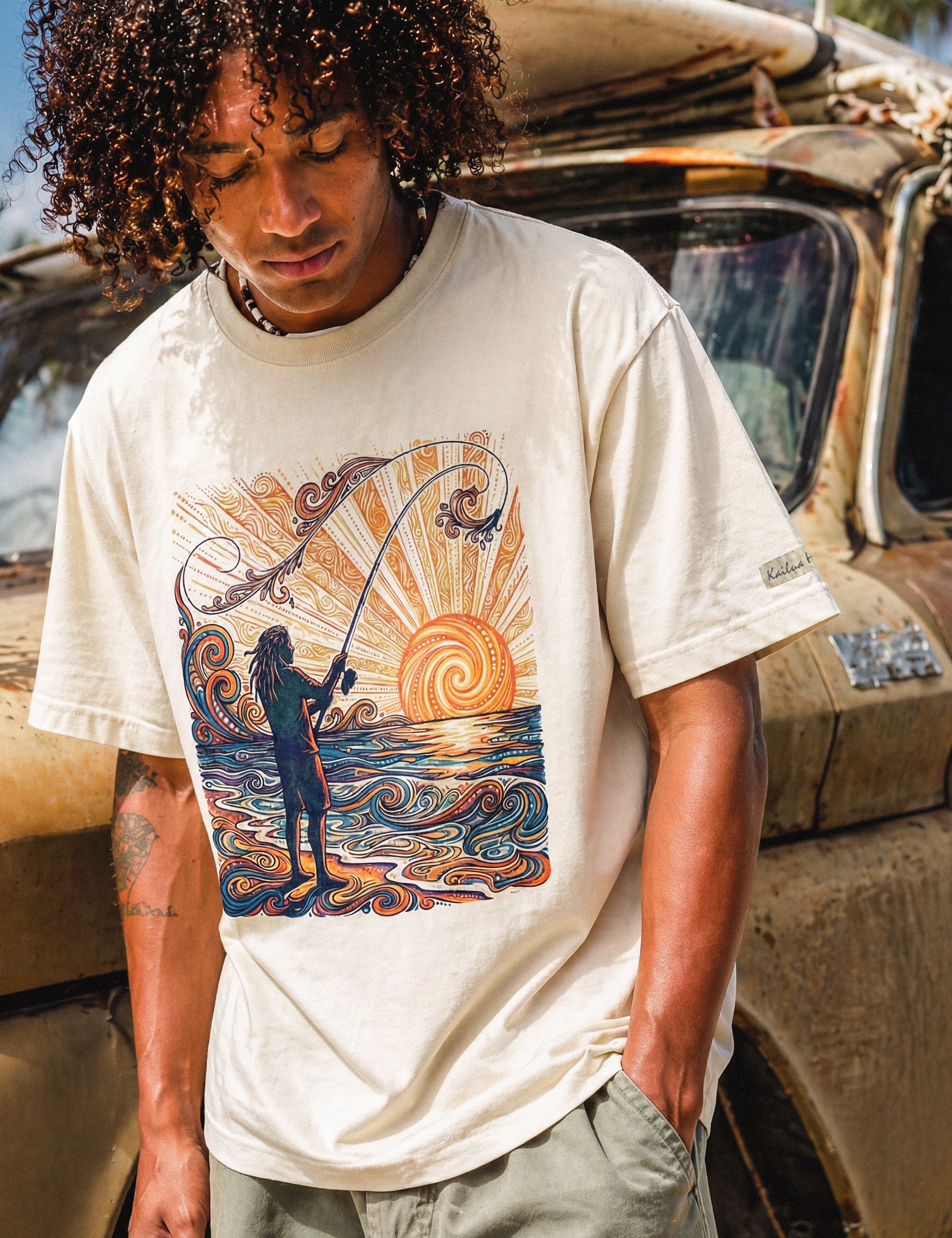 man standing in front of a truck wearing a pearl colored shirt with a colorful graphic of a person fishing