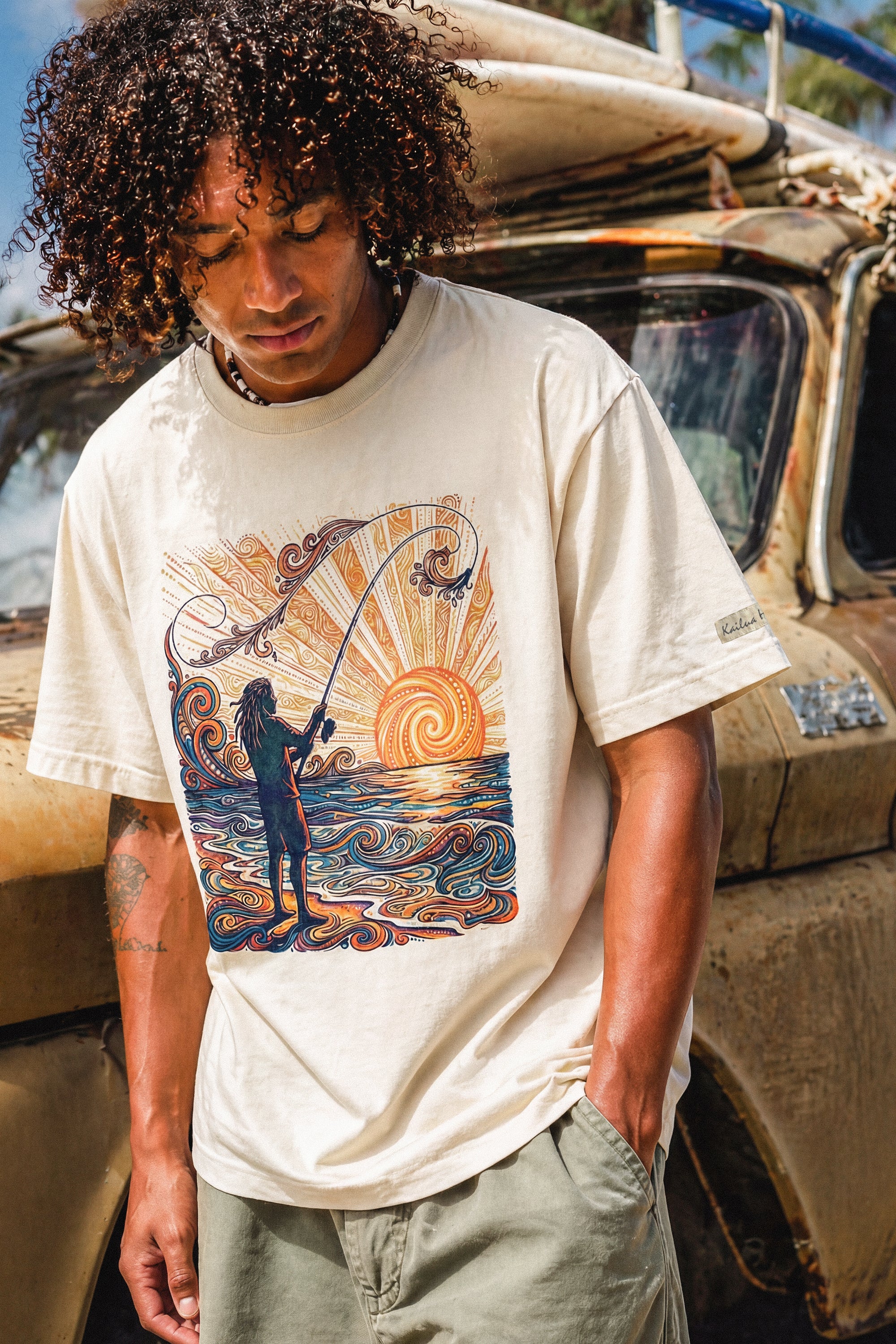 man standing in front of a truck wearing a pearl colored shirt with a colorful graphic of a person fishing