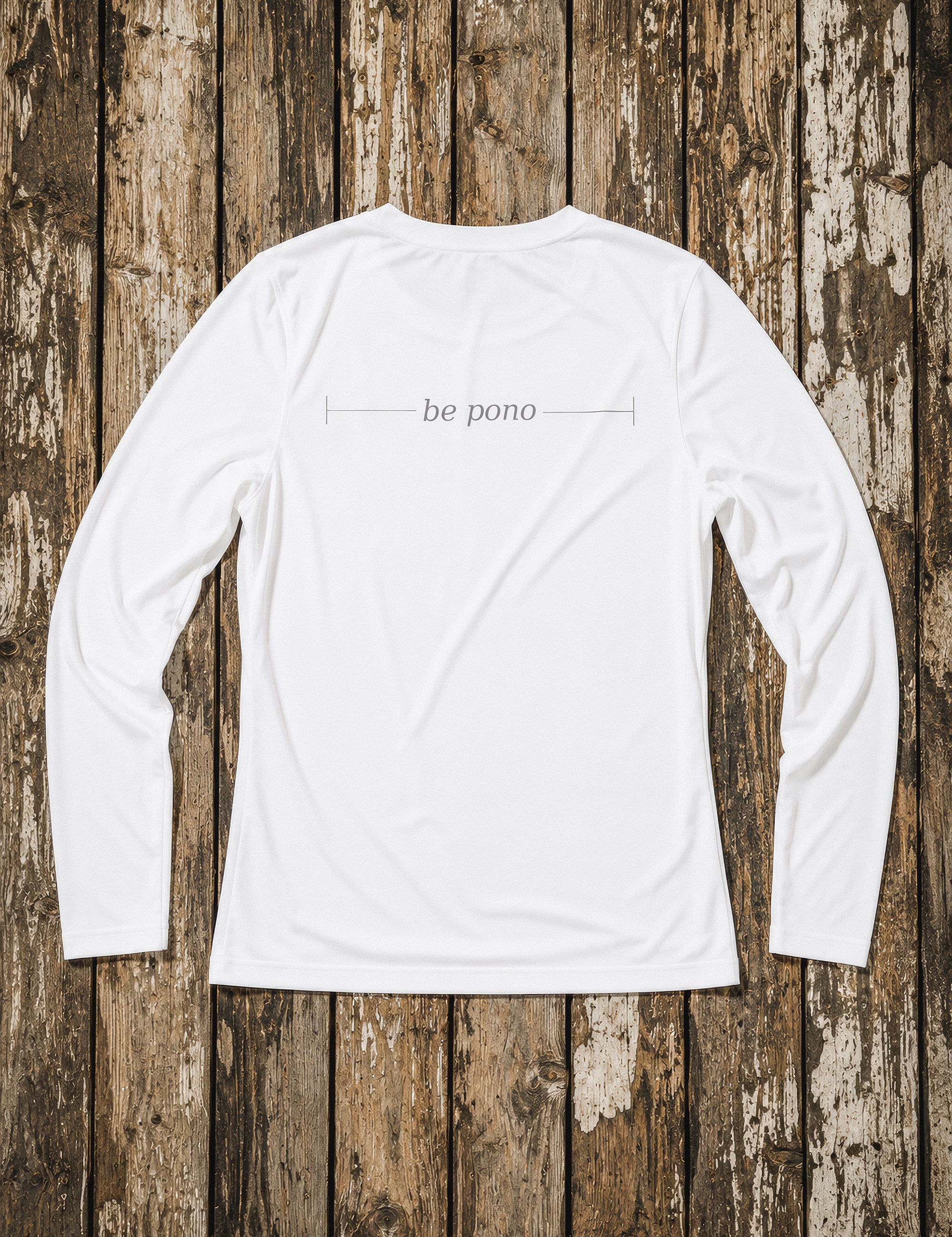 White long-sleeve shirt with 'be pono' text on a wooden background