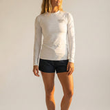 Woman wearing a white long-sleeve shirt and black shorts on a plain background