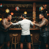 playful bar scene: man seen from behind in white rash guard with “be pono” back print, breaking up a fight in a tiki bar