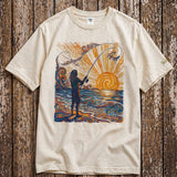 a pearl colored shirt with a colorful graphic of a person fishing laying on a wood floor