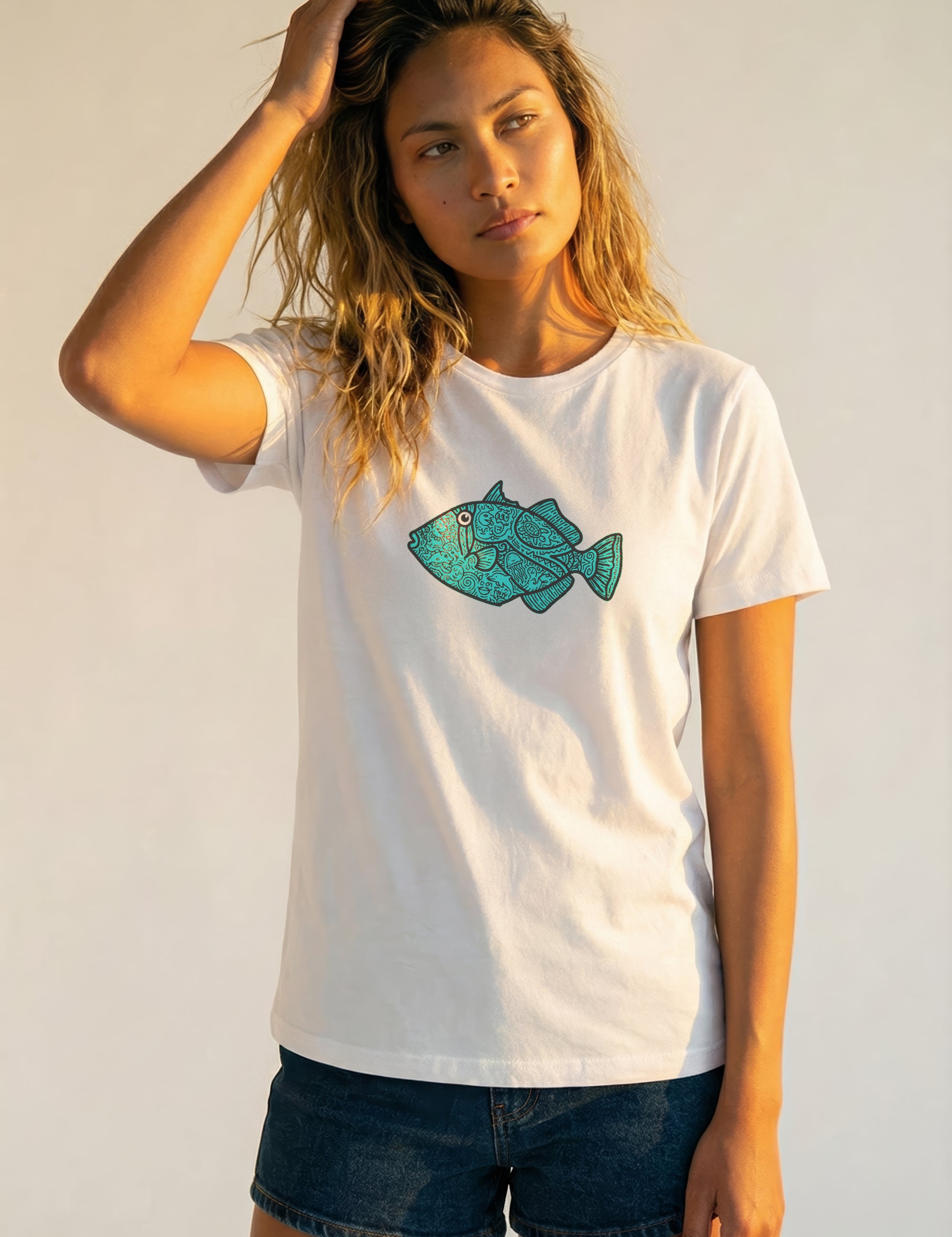 Woman wearing a white t-shirt with a blue fish graphic on a plain background