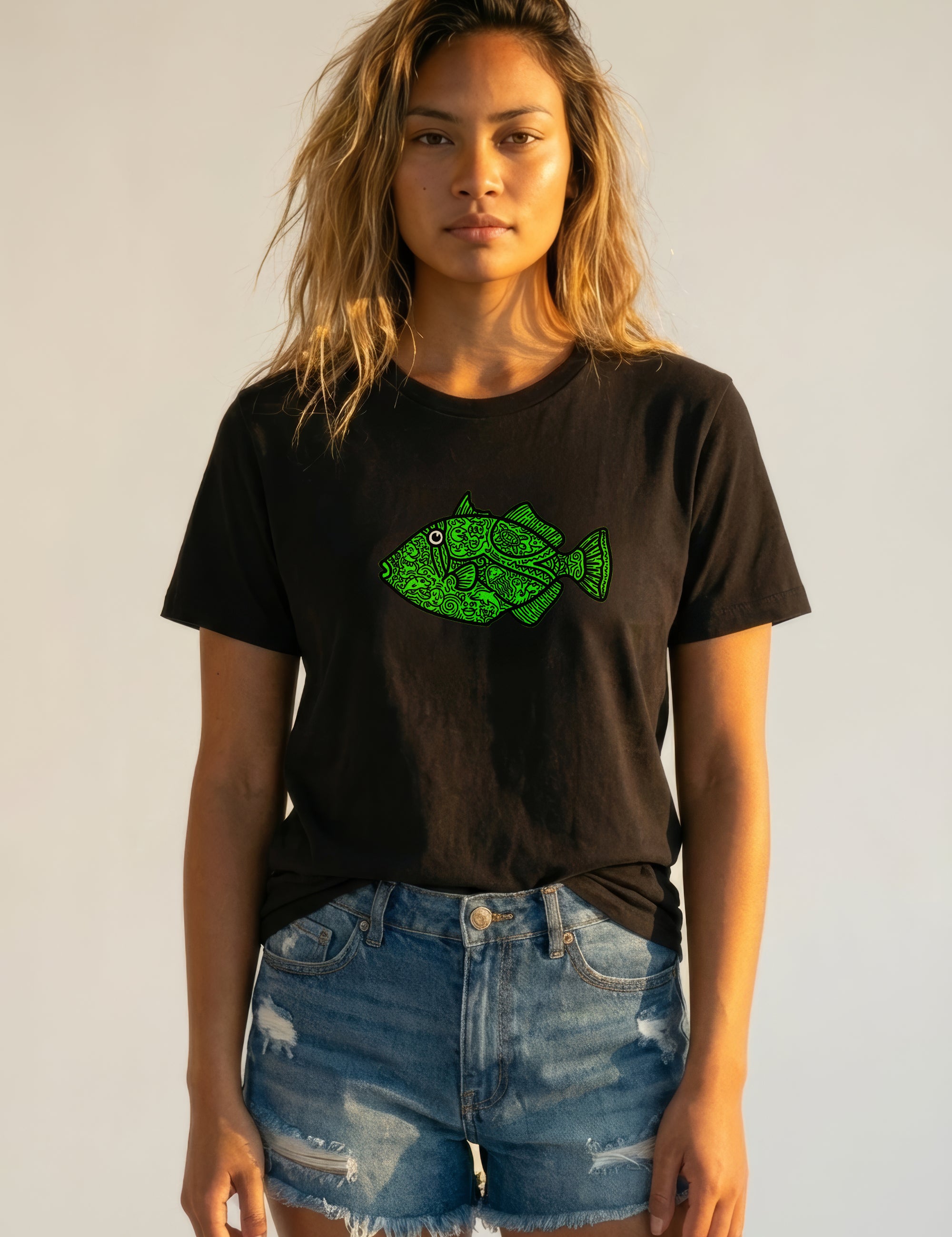 Woman wearing a black t-shirt with a green fish graphic design on a plain background