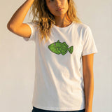 Woman wearing a white t-shirt with a green fish graphic on a plain background