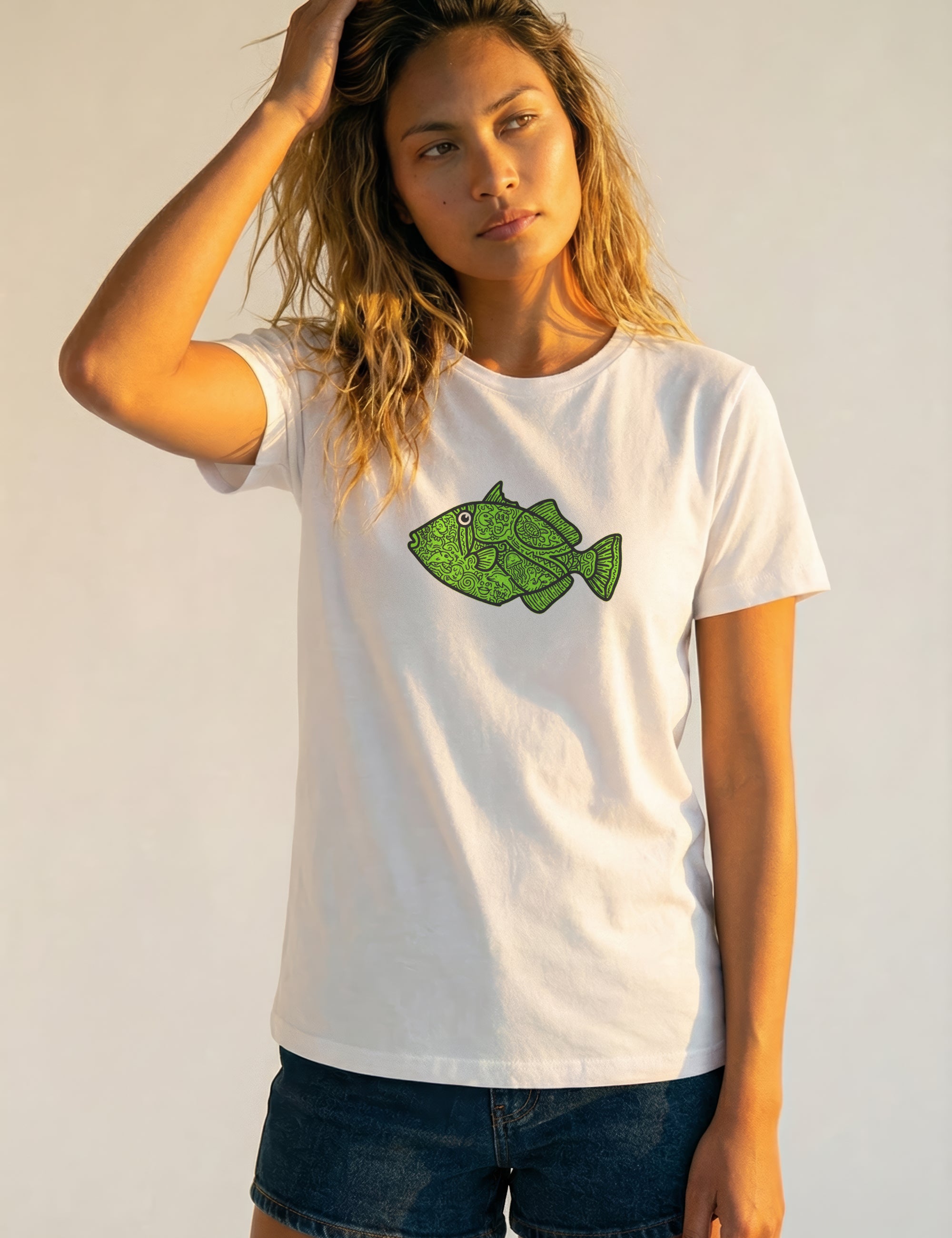 Woman wearing a white t-shirt with a green fish graphic on a plain background