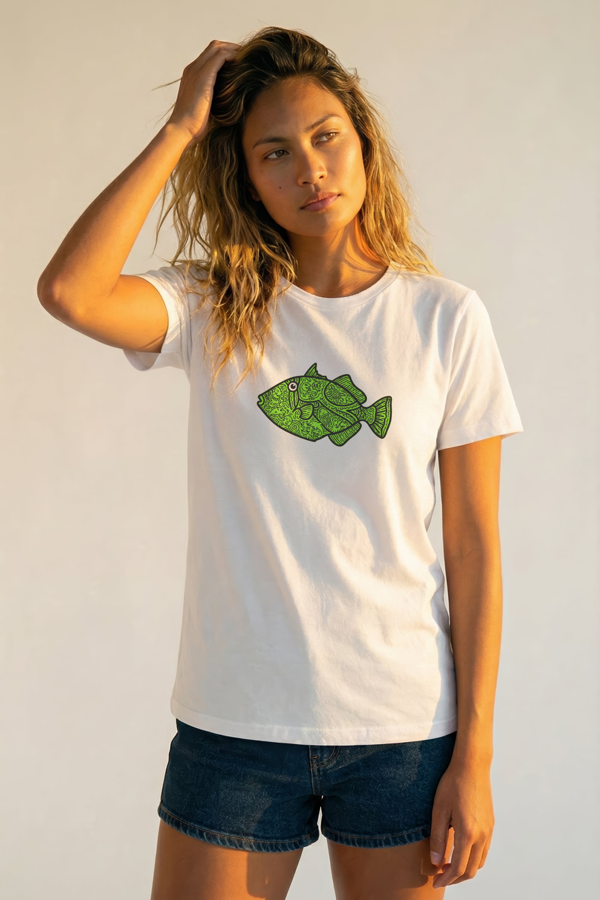 Woman wearing a white t-shirt with a green fish graphic on a plain background