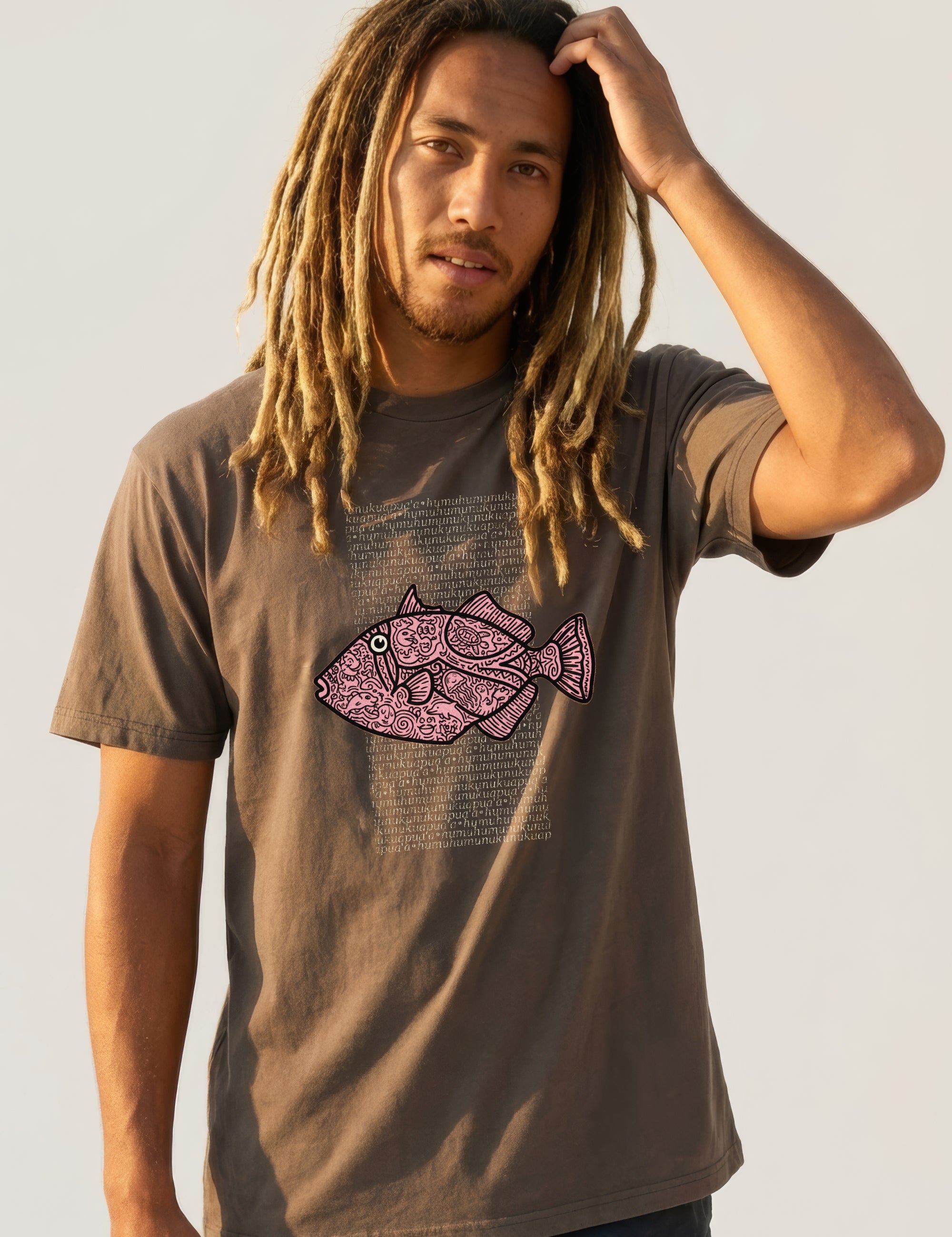 Man wearing a brown t-shirt with a pink fish graphic on a plain background