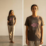 woman wearing a brown t-shirt with a pink fish design on the front