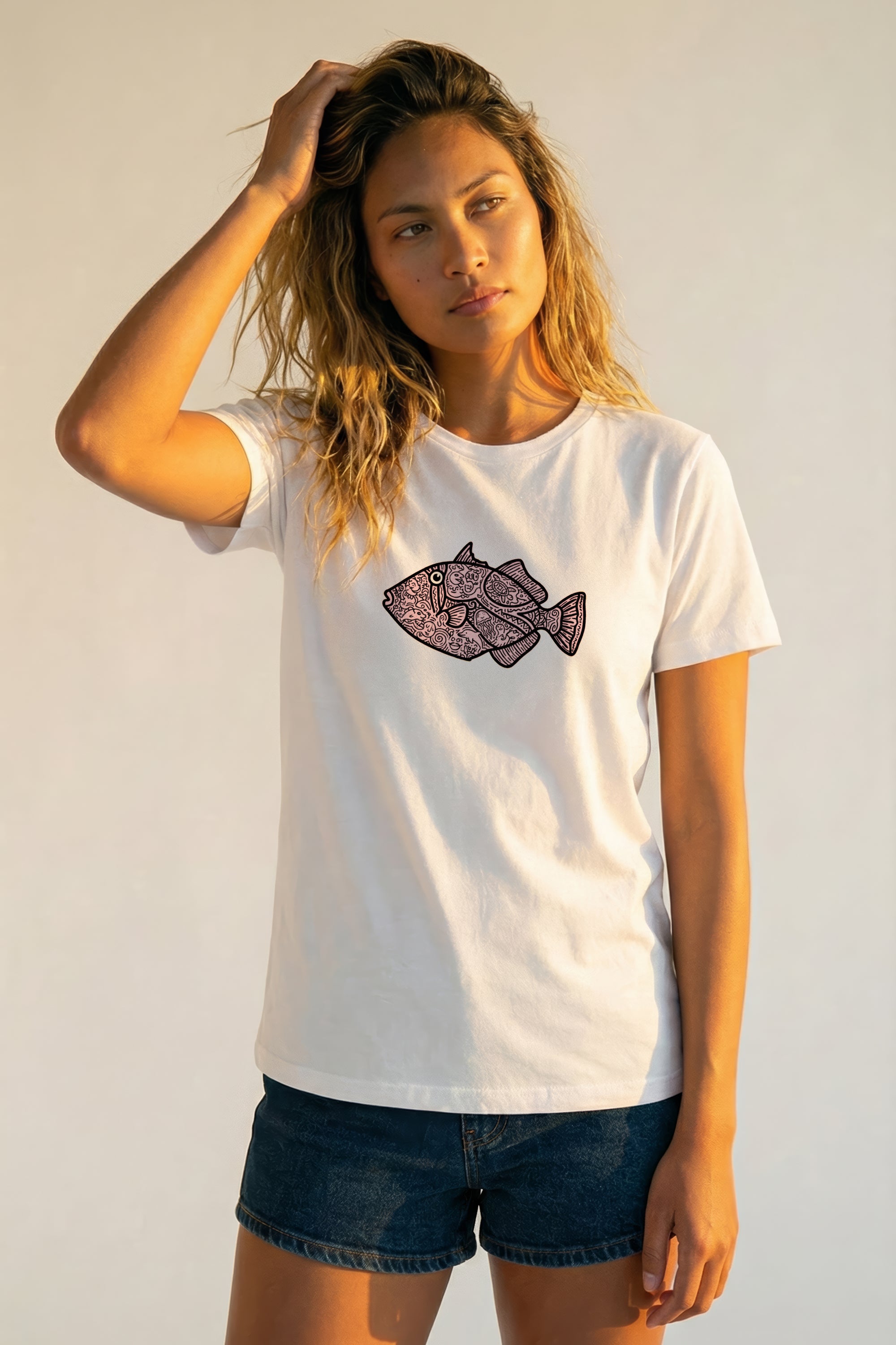 Woman wearing a white t-shirt with a pink fish graphic on a plain background