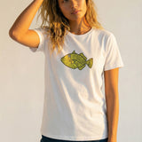 Woman wearing a white t-shirt with a yellow fish graphic on a plain background