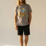 Man wearing a gray t-shirt with kailua hi logo design and black shorts on a plain background