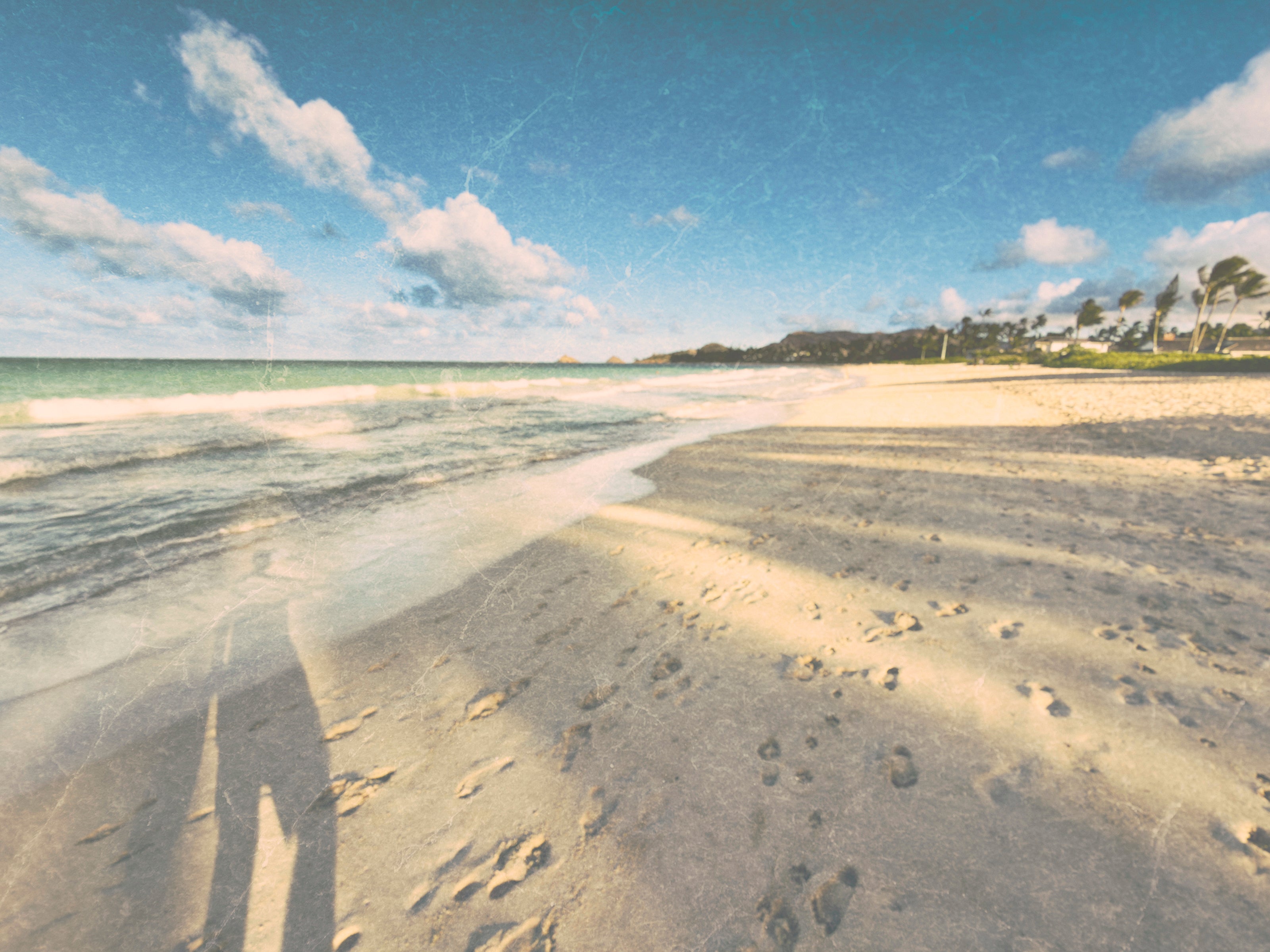 kailua beach scene with footprints in the sand and a clear sky.