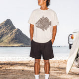 a man wearing a pearl colored t-shirt with a fish graphic standing on a beach
