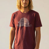 Man wearing a burgundy t-shirt with a white man-o-war with peace signs graphic design on a plain background