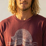 man wearing burgundy t-shirt with man-o-war design filled with peace signs against a white background