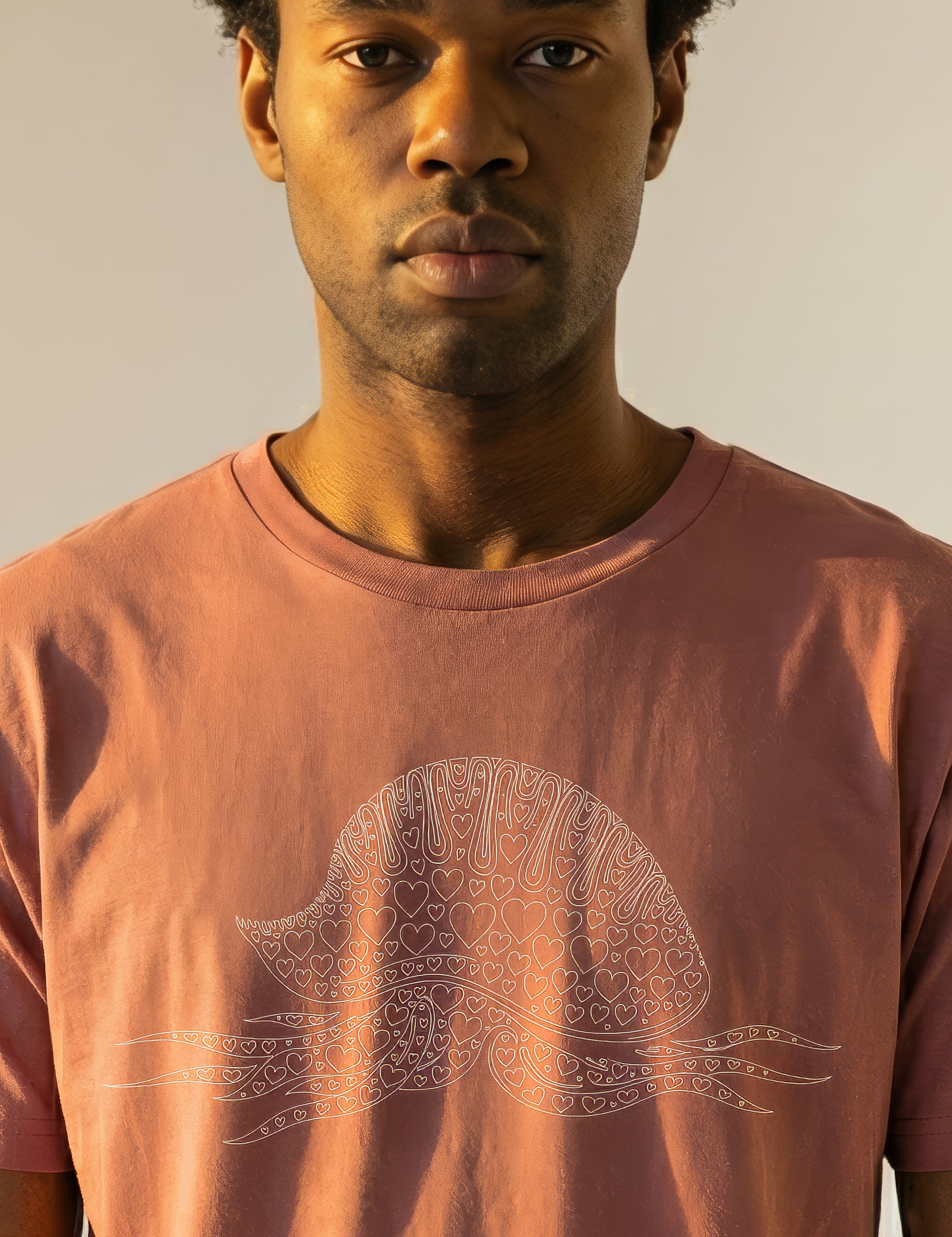 Man wearing coral t-shirt with man-o-war design filled with hearts