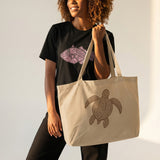 Woman holding a beige tote bag with a turtle design against a plain background