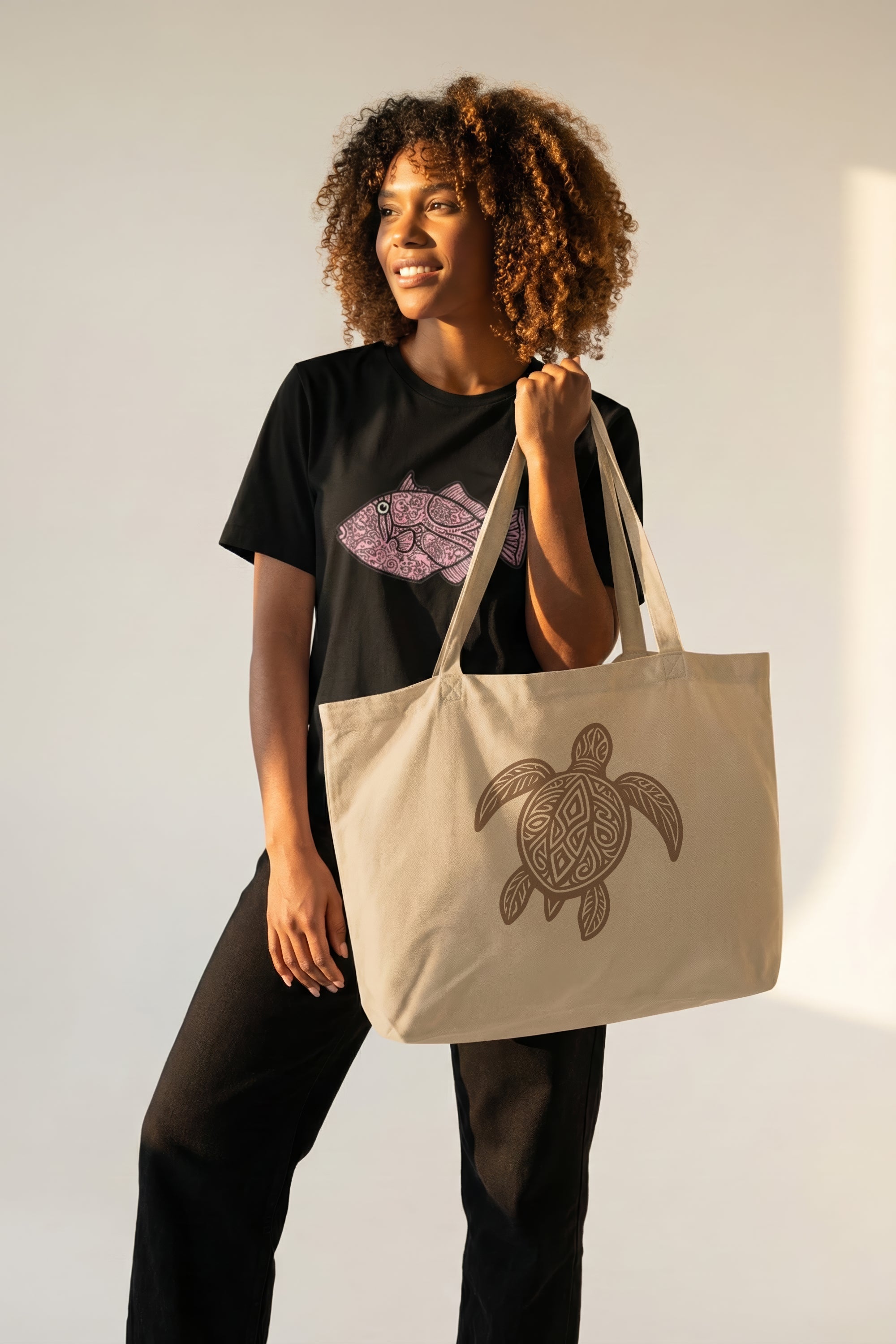 Woman holding a beige tote bag with a turtle design against a plain background