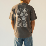 Person wearing a dark gray t-shirt with white cannabis leaf design on the back, standing against a plain background.