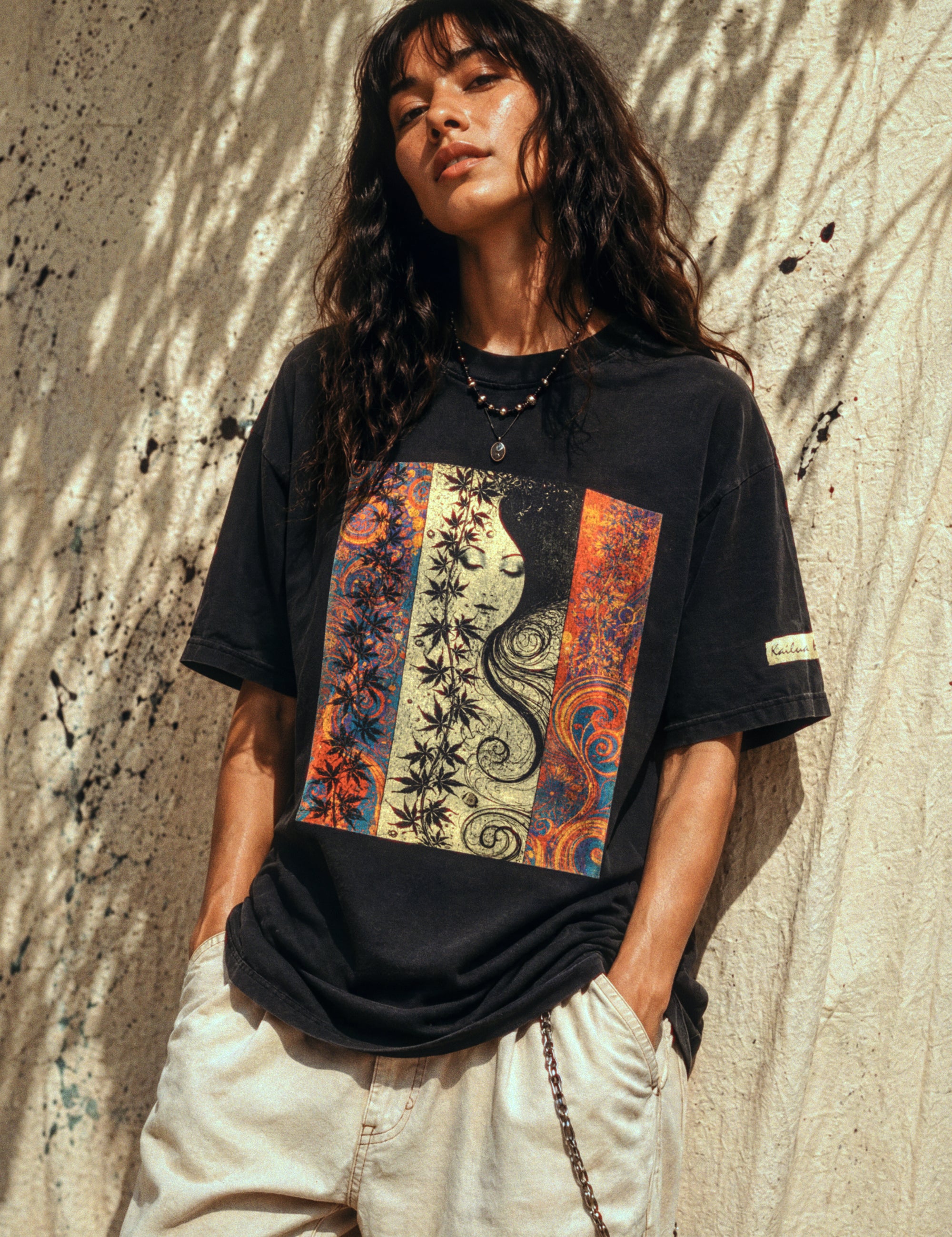 woman wearing a black t-shirt with a colorful graphic design against a textured wall.