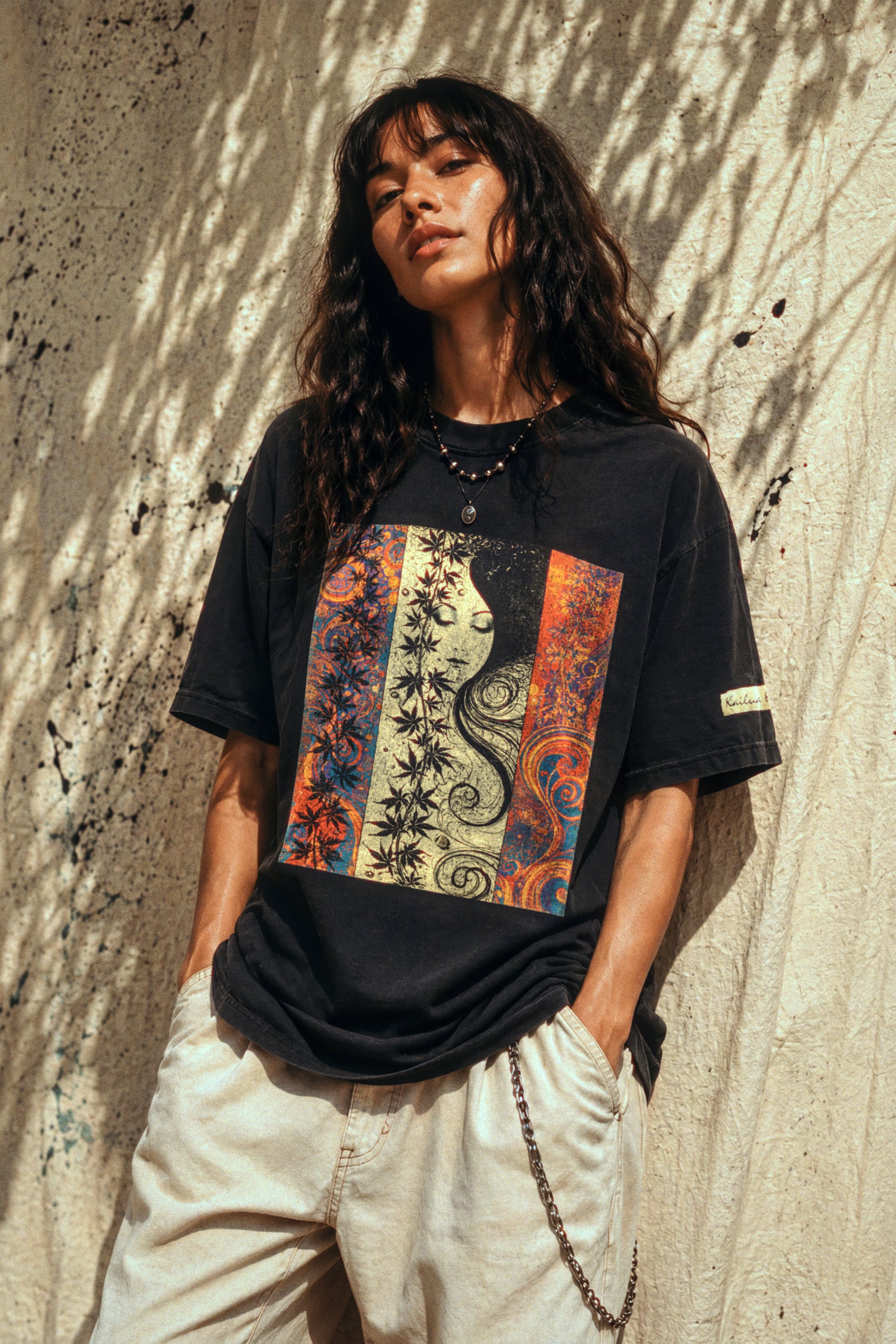 woman wearing a black t-shirt with a colorful graphic design against a textured wall.