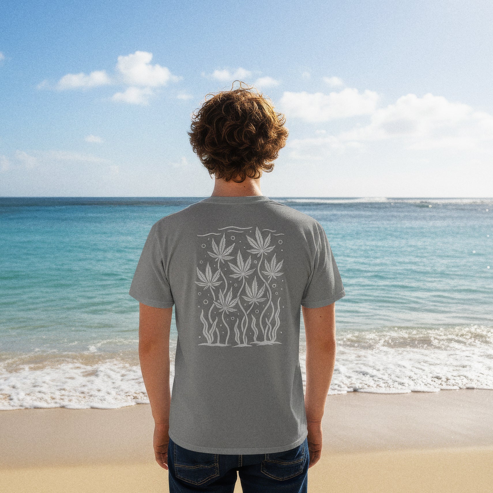 man on kailua beach wearing grey pocket tee; back features off-white “sea-weed” panel of floating leaf motifs and seagrass
