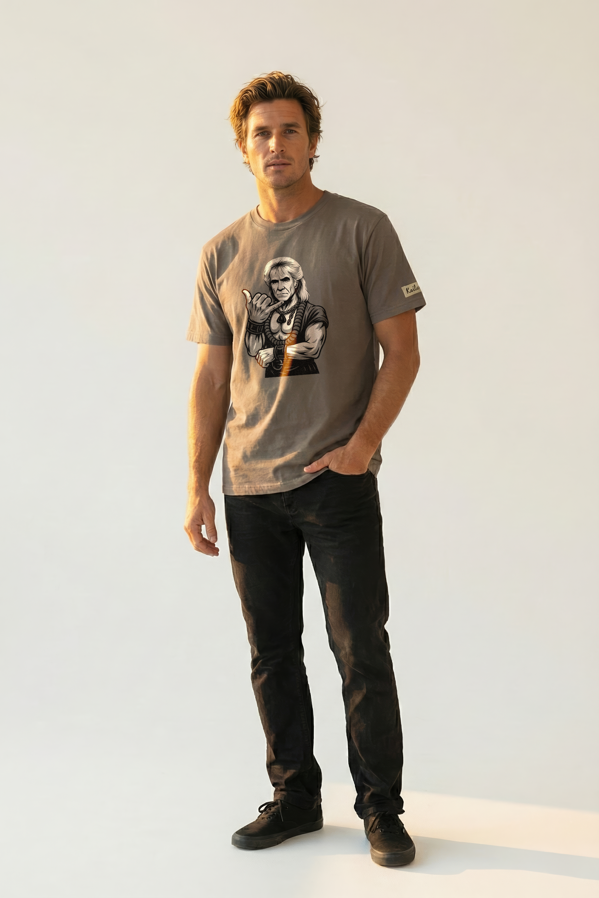 Man wearing a brown graphic t-shirt with a design of a man giving the shaka hand sign on a plain background