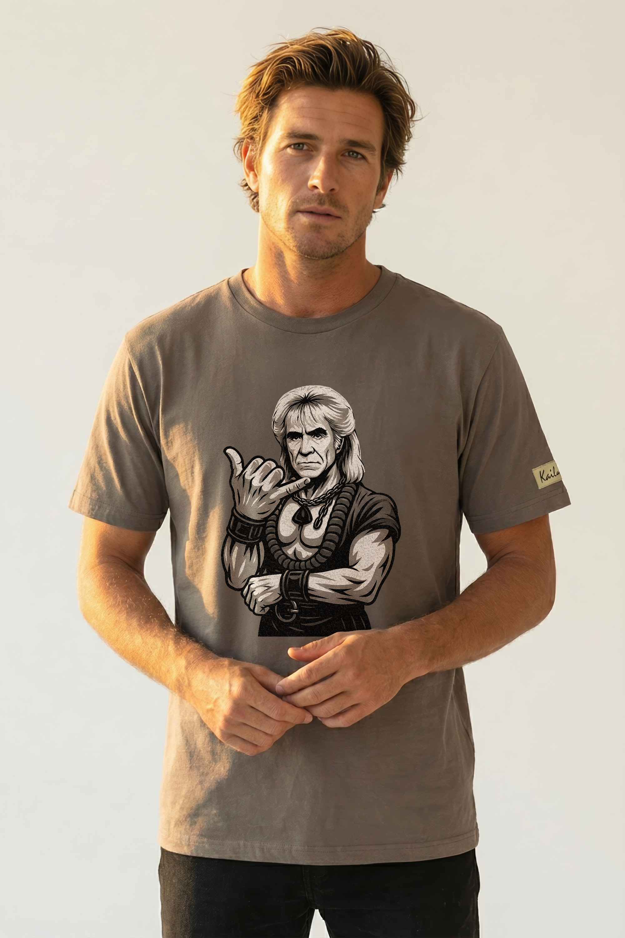 Man wearing a t-shirt with a graphic design of a muscular figure giving the shaka hand sign on a plain background