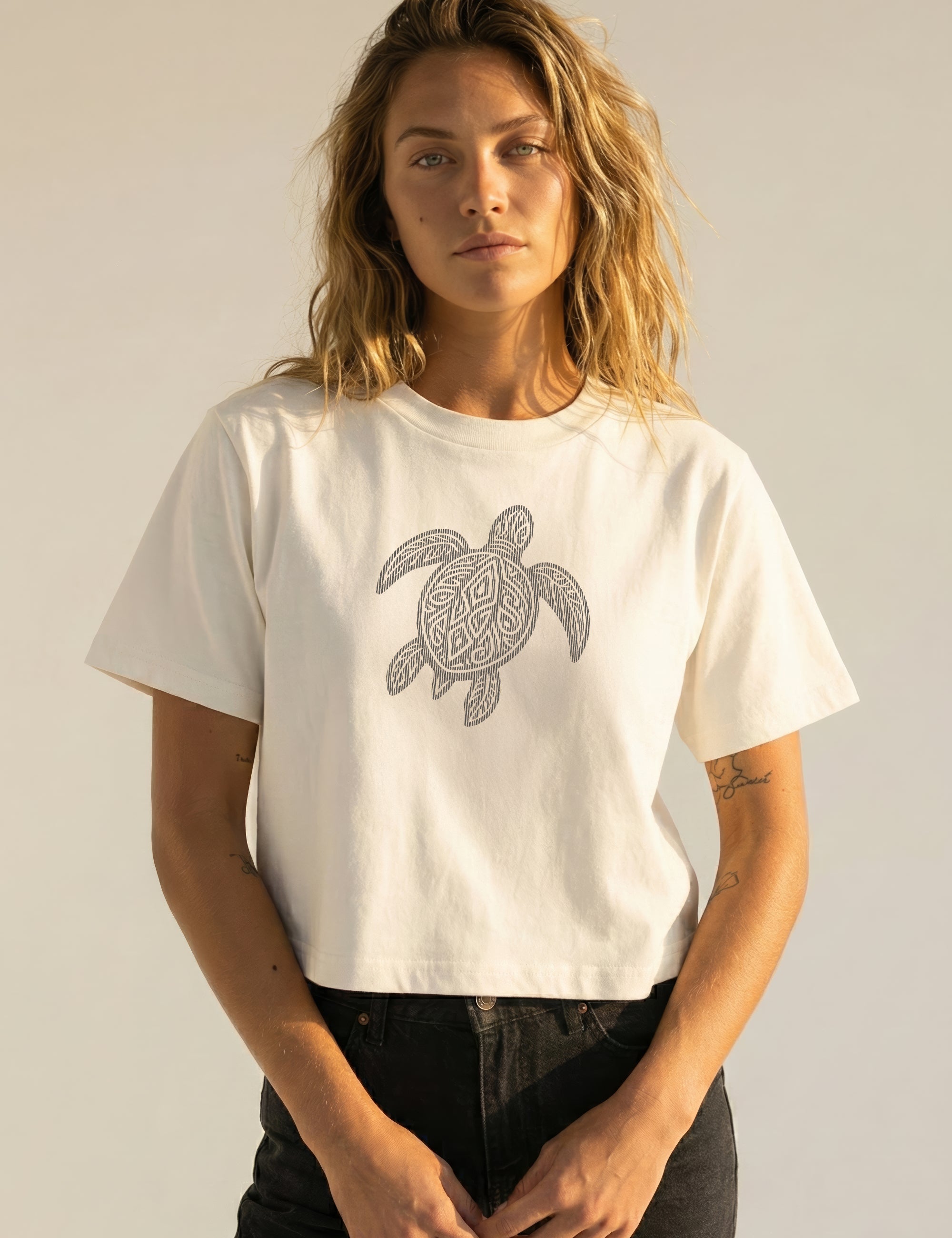 Woman wearing a white t-shirt with a turtle design on a plain background