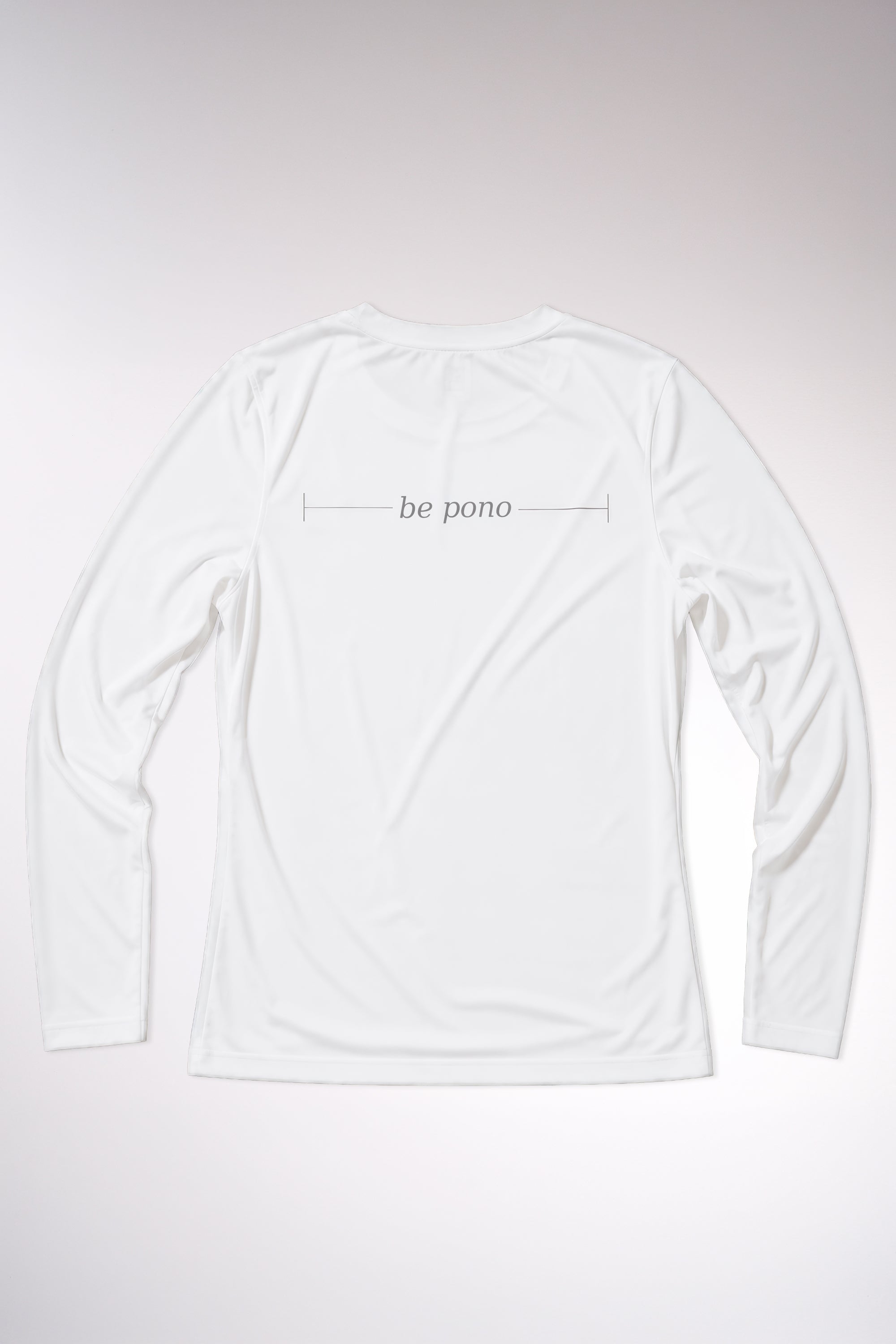 kailua hi surf tees be pono women's long sleeve upf 50 sunshirt in white – studio flat lay product shot of the back of the shirt. features the minimalist text be pono printed across the shoulders with clean horizontal accent lines, showcasing the relaxed performance fabric build and athletic crew neck against a neutral background