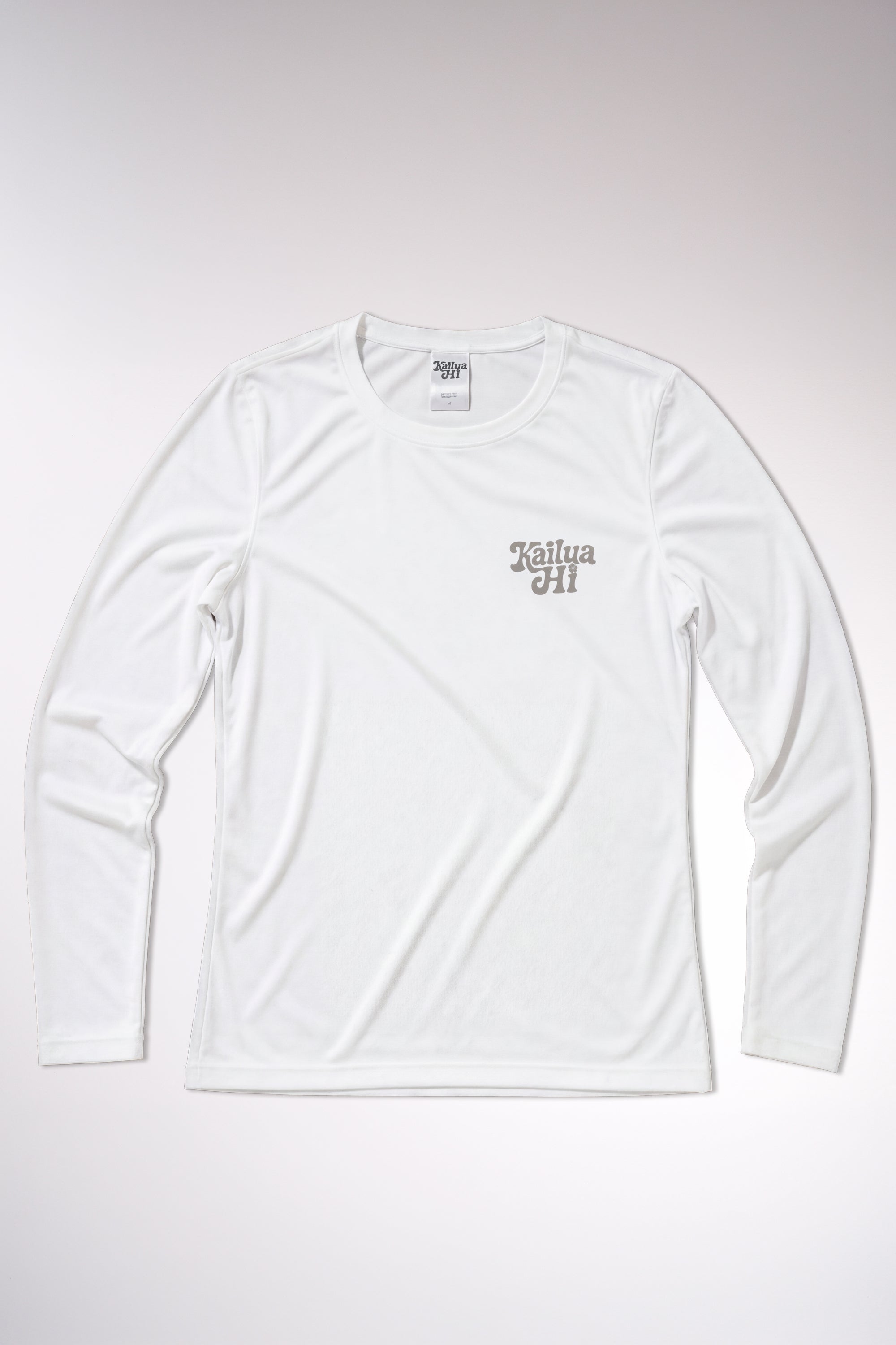 kailua hi surf tees be pono women's long sleeve upf 50 sunshirt in white – studio flat lay product shot of the front of the shirt. features a retro gray script kailua hi logo printed on the left chest, an athletic crew neckline, and a visible interior kailua hi woven neck label, showcasing the clean texture of the performance uv protective fabric against a neutral background