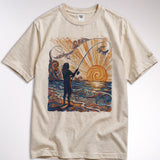 kailua hi surf tees catching rays women's luxe tee in pearl – studio flat lay product shot showing the full front graphic. features a detailed woodcut style illustration of a fisherman silhouette casting a rod into swirling orange and yellow sunset ocean waves. includes a relaxed crew neckline, interior kailua hi woven neck label, and custom sleeve tag against a neutral background