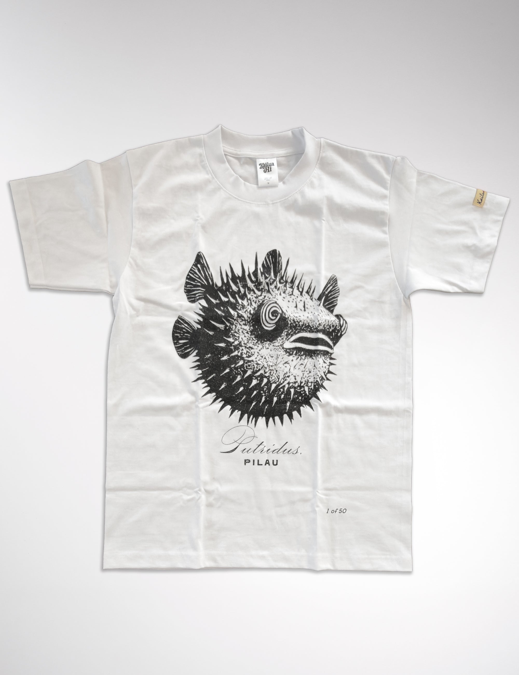 kailua hi surf tees pilau premium tee in white – studio flat lay product shot showing the full front spiky black and white porcupine fish graphic with a spiral eye detail. features a relaxed crew neckline, interior kailua hi woven neck label, sleeve tag, cursive putridus text, capital pilau text, and a 1 of 50 limited print marker against a neutral background