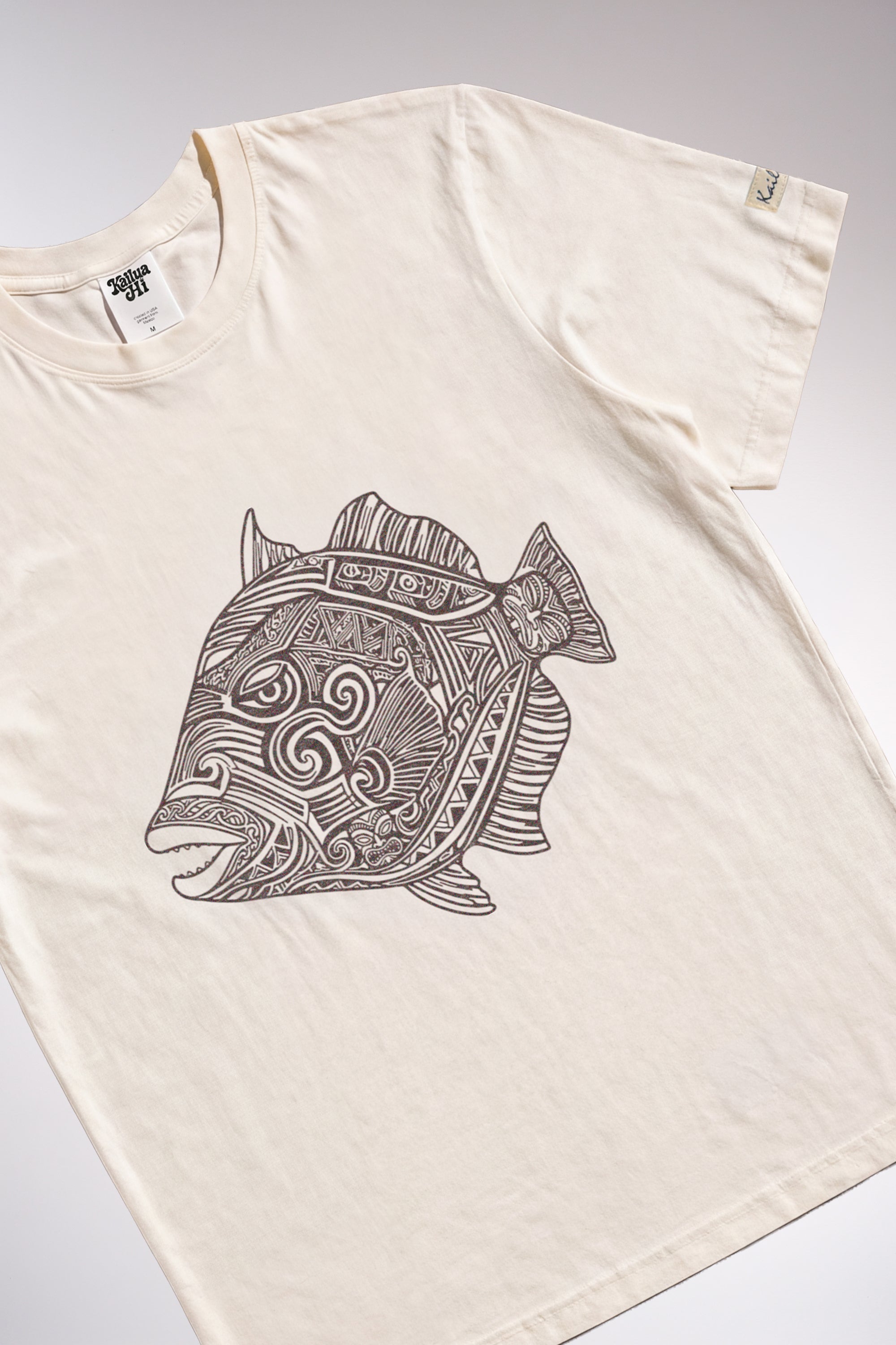 kailua hi surf tees humuhumu luxe tee in pearl brown – product lifestyle video showcasing men's and women's beach styling. features the relaxed casual fit, premium fabric drape, and detailed brown intricate tribal woodcut style humuhumu fish illustration in motion